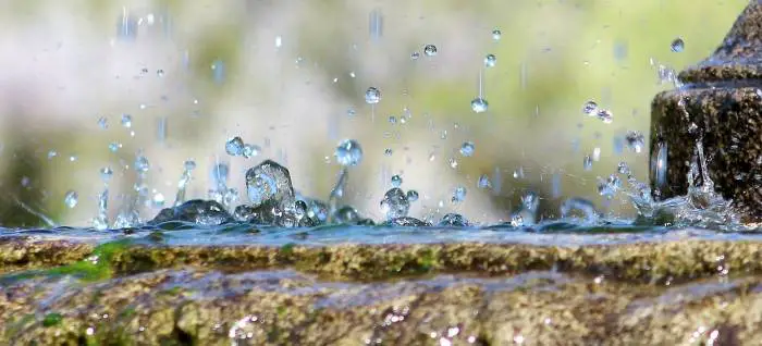 Close-up of water droplets splashing on the edge of a water fountain, capturing the essence of movement.