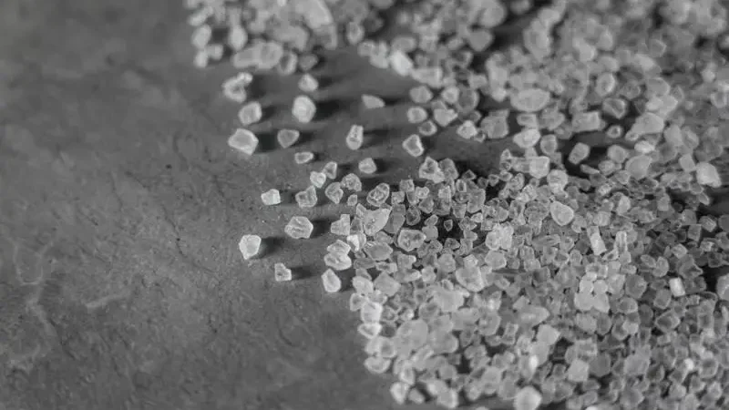 Close-up of scattered Epsom salt crystals on dark slate.