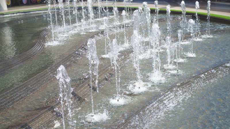 Serene water fountain jets arching gracefully, creating a tranquil, quieter ambience with rippling water patterns.