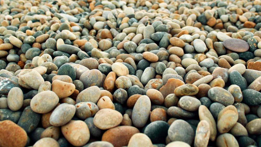 A variety of rounded multi-colored gravel stones, illustrating a potential texture and color palette for a gravel patio surface.