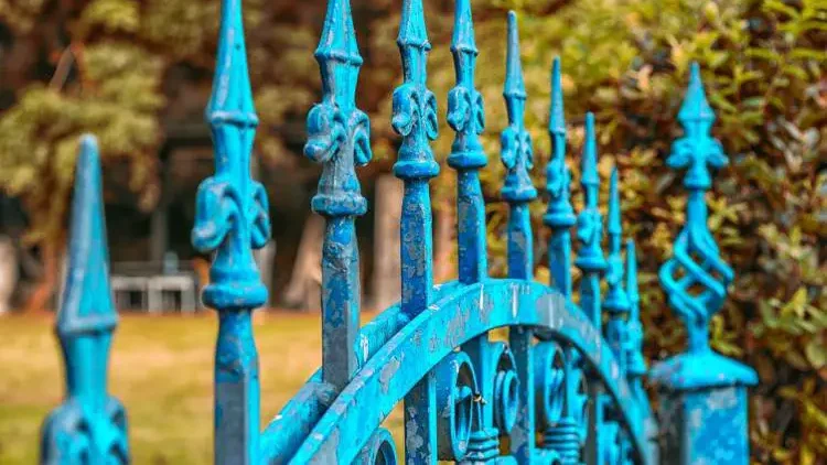 Peeling blue paint on an ornate iron gate, evoking the sound of a gate slamming shut.