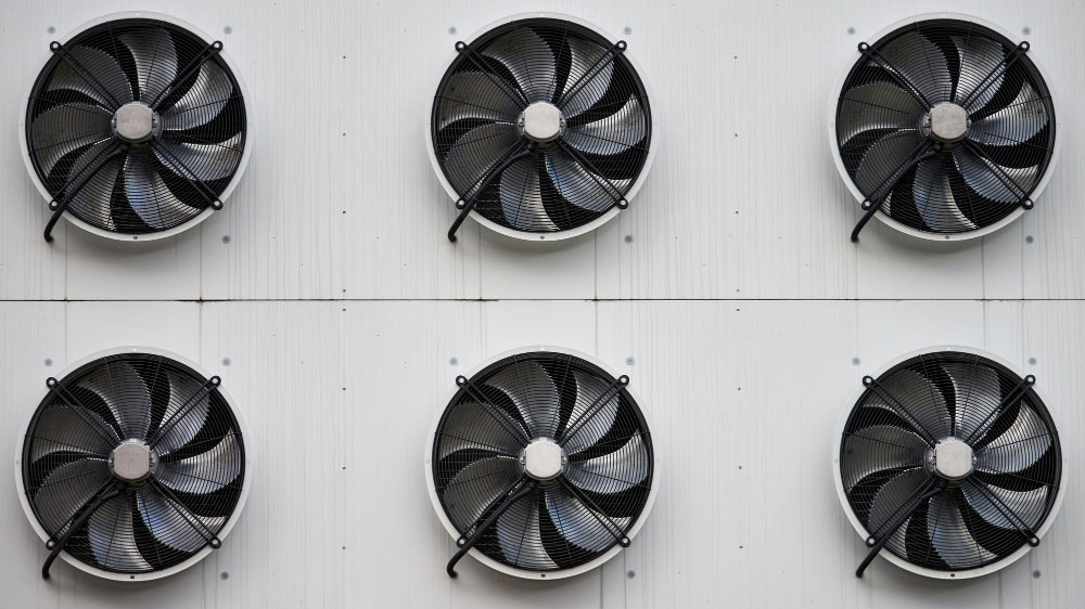 Six duct booster fans mounted in a grid pattern on a white wall for efficient air circulation.