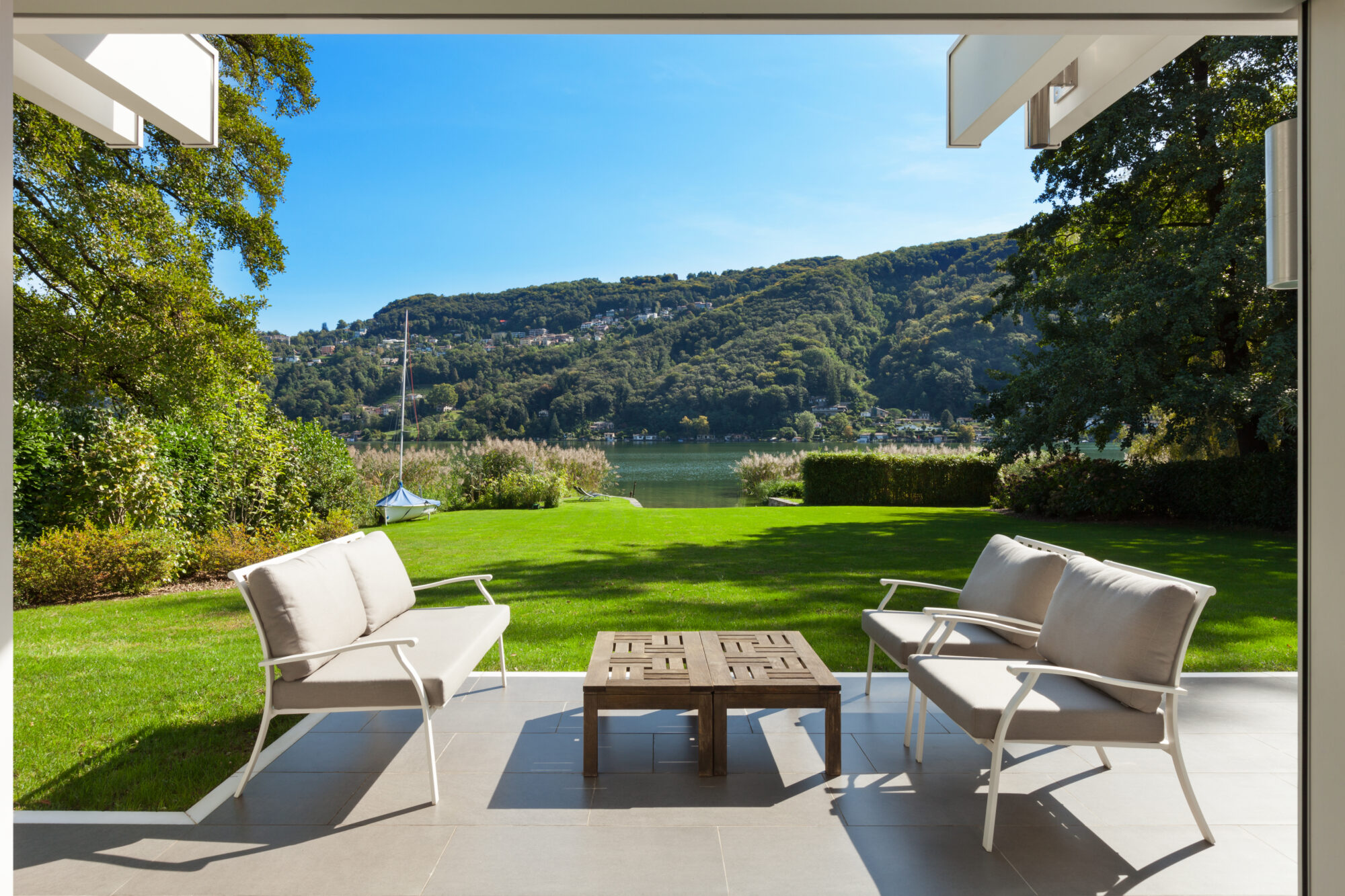 Serene garden patio overlooking a lake, ideal for using a weed eater before relaxing.